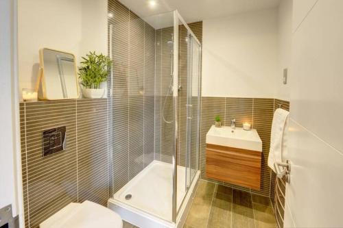 a bathroom with a shower and a toilet and a sink at Modern & Stylish 2BR Apartment - Queens House in Coventry