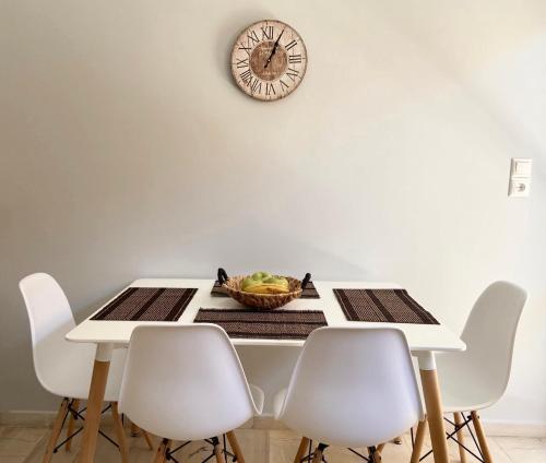 a table with white chairs and a clock on the wall at Aussie Apartments in Sikéa