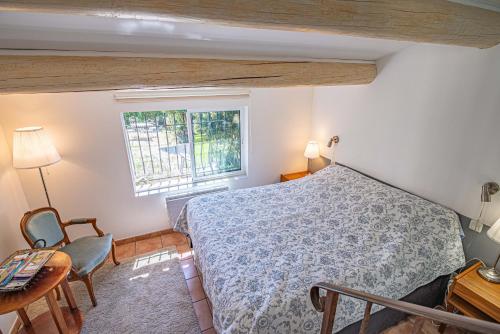 1 dormitorio con cama, escritorio y ventana en La Roubine, Velleron, en Velleron