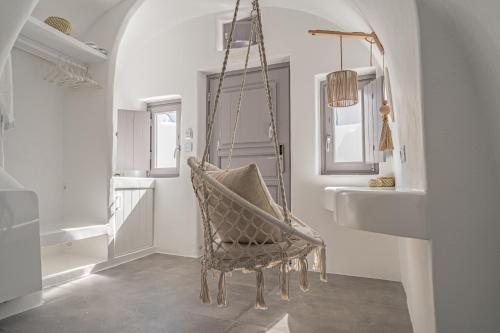 a bathroom with a chair sitting next to a sink at Eternity Suites Santorini in Fira