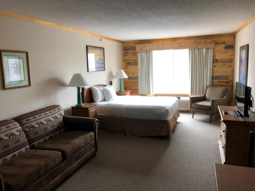 een hotelkamer met een bed en een bank bij Flat Creek Lodge in Hayward