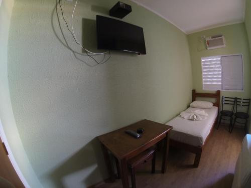 a small room with a bed and a tv on the wall at Hotel Paris in Jundiaí