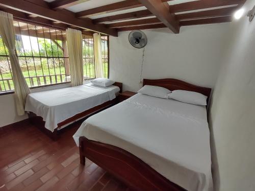 two beds in a room with two windows at CASA QUINTA BENDITO PARAÍSO in Melgar