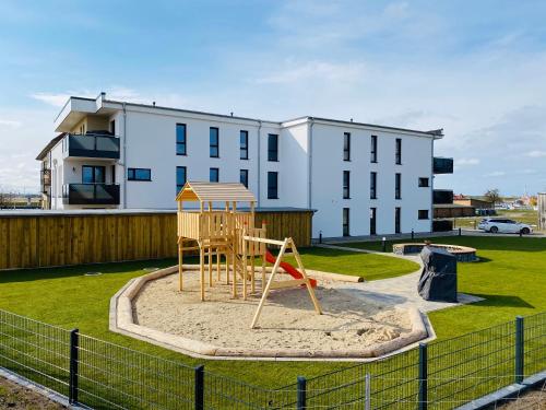 une aire de jeux dans un parc en face d'un bâtiment dans l'établissement Haus Meerruhe Karlshagen Apartment 1-6, à Karlshagen