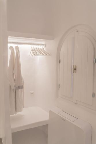 a white bathroom with a toilet and a white cabinet at Eternity Suites Santorini in Fira