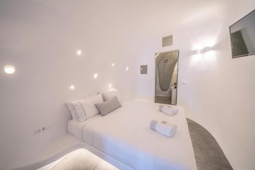 a white bedroom with a bed with two towels on it at Eternity Suites Santorini in Fira