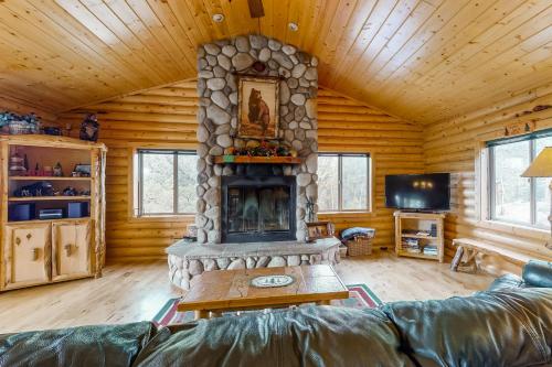 a living room with a stone fireplace in a log cabin at Bear Crossing in Divide