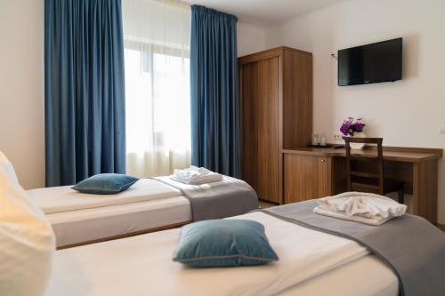 a hotel room with two beds and a television at Pensiunea Transilvania in Sibiu