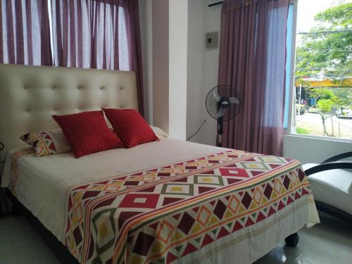 a bedroom with a bed with red pillows and a window at Apartamento oasis del norte in Cali