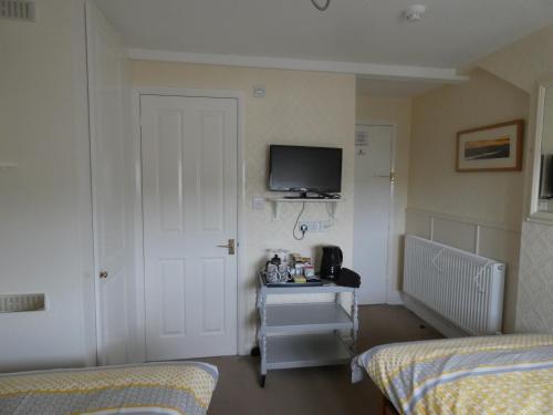 a bedroom with two beds and a tv on the wall at White Rose in Windermere