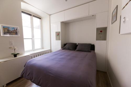 une chambre avec un lit dans une pièce blanche dans l'établissement L'Ecluse - Studio Cosy, Calme, Hyper-Centre Strasbourg, à Strasbourg