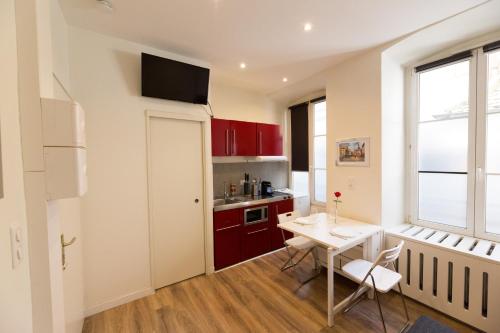 une cuisine avec des placards rouges et une table avec des chaises dans l'établissement L'Ecluse - Studio Cosy, Calme, Hyper-Centre Strasbourg, à Strasbourg