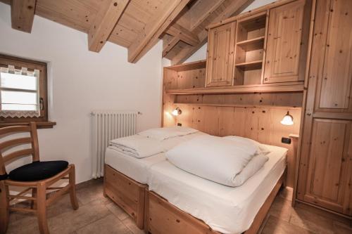 a bedroom with a bed and a chair and wooden cabinets at Baita Kate in Livigno