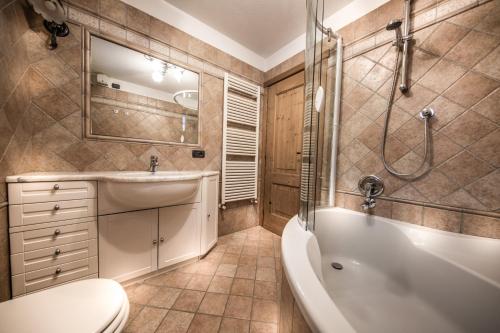 a bathroom with a tub and a toilet and a sink at Baita Kate in Livigno