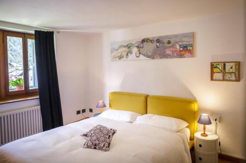 a bedroom with a white bed with a yellow headboard at LA PITA AGORDINA in Cancellade