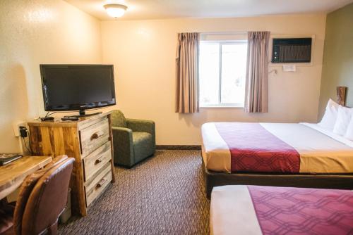 a hotel room with two beds and a flat screen tv at Econo Lodge, Downtown Custer Near Custer State Park and Mt Rushmore in Custer