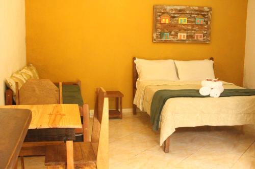 a bedroom with a bed and a table and a chair at Pousada Mar & Vida e Doçaria in Paraty