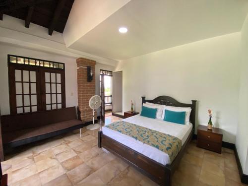 a bedroom with a bed with blue pillows and a window at Finca Hotel La Esperanza in Montenegro