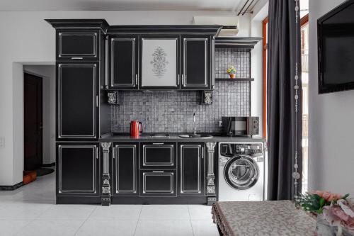 a kitchen with black cabinets and a washing machine at Elegant city center apartment in Odesa