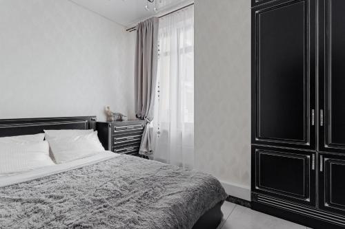 a black and white bedroom with a bed and a dresser at Elegant city center apartment in Odesa