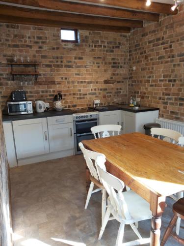 a kitchen with a wooden table and a brick wall at The coach house in Llansantffraid-ym-Mechain