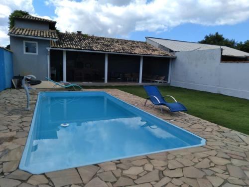 a swimming pool with two chairs and a house at Itaipuaçu Maravilhosa in Maricá