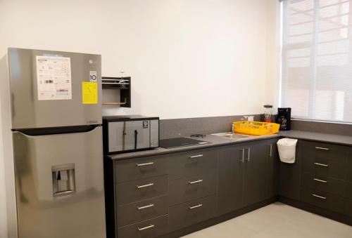 a kitchen with a stainless steel refrigerator and gray cabinets at Edificio Tofino in Quito