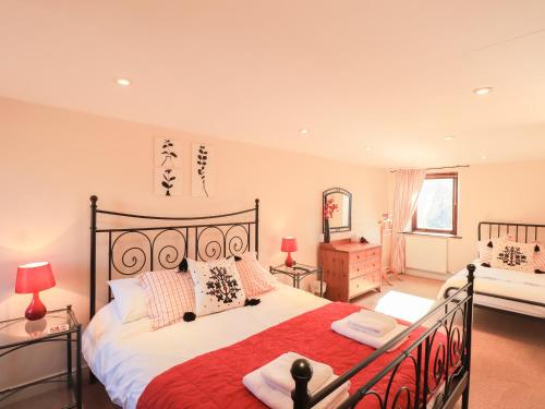 a bedroom with a large bed with a red blanket at Horseshoe Cottage in Wigton