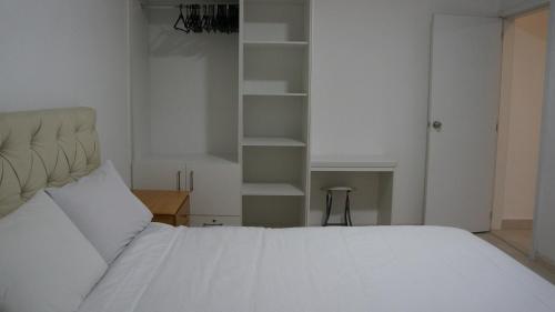 a bedroom with a large white bed and shelves at Edificio Tofino in Quito