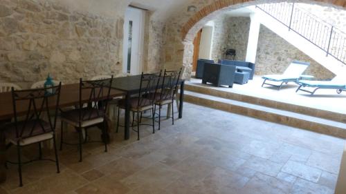 una sala da pranzo con tavolo e sedie e un muro di pietra di La Pause Ardéchoise a Saint-Remèze