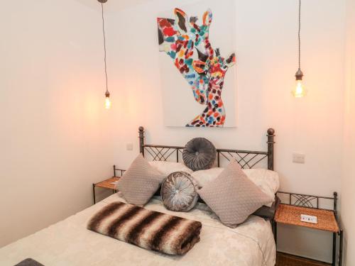 a bedroom with a bed with pillows and a painting at The Snug in Chathill