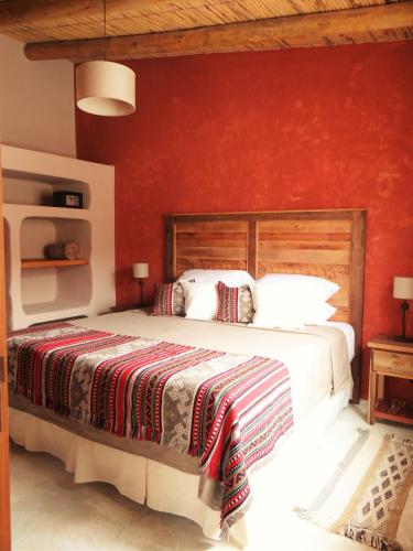 a bedroom with a large bed with a red wall at Tierra Quebrada Cabañas in Purmamarca