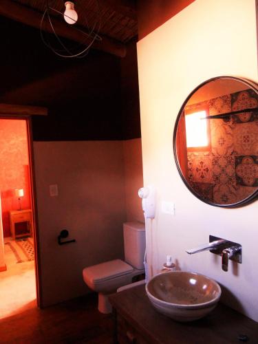 a bathroom with a sink and a toilet and a mirror at Tierra Quebrada Cabañas in Purmamarca