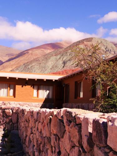 a house with a stone wall in front of a mountain at Tierra Quebrada Cabañas in Purmamarca