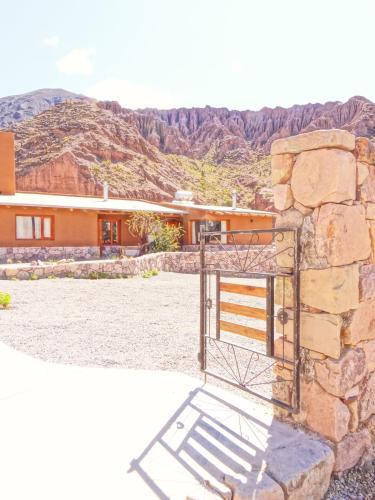 a house with a gate in front of a mountain at Tierra Quebrada Cabañas in Purmamarca