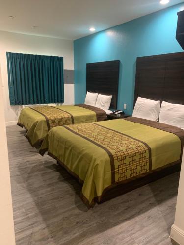 2 camas en una habitación con paredes azules en LOTUS INN en Houston