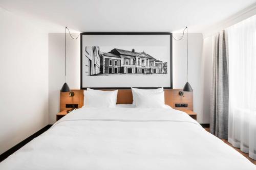 a bedroom with a white bed and a black and white picture at MERCURE KLAIPEDA CITY HOTEL, Meetings, Events, Restaurant & Bar - Accor Group, Pet Stay FREE in Klaipėda
