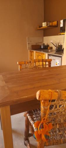 a wooden dining table with chairs and a kitchen at Tierra Quebrada Cabañas in Purmamarca