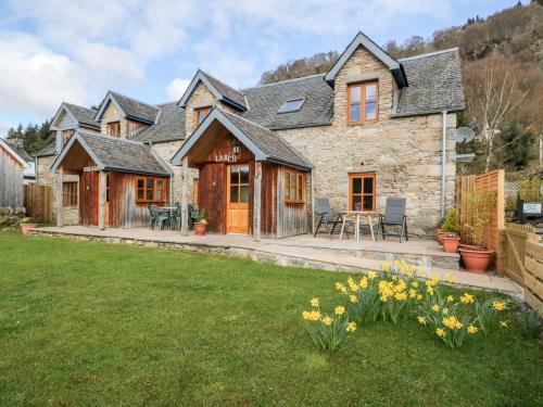 a large stone house with a yard at Larch Cottage in Weem