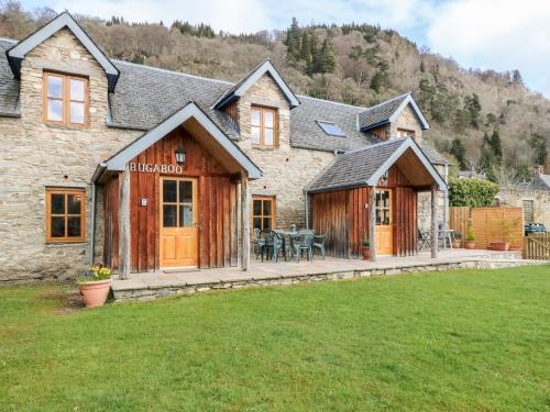 a large stone house with a patio in a yard at Bugaboo Cottage in Weem