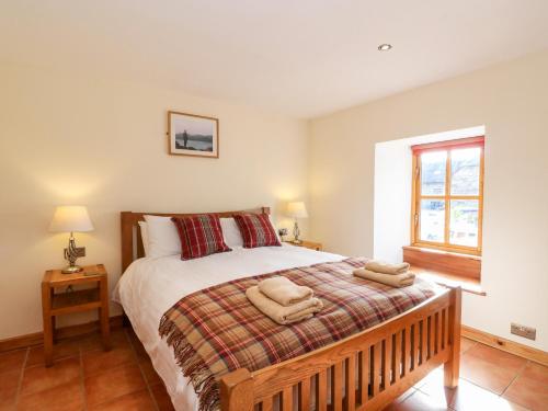 a bedroom with a bed with two towels on it at Larch Cottage in Weem