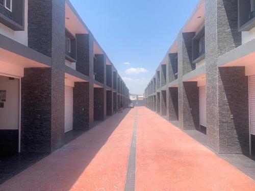 an empty hallway of a building with a red brick sidewalk at Motel Pedregal Suites in San Juan del Río