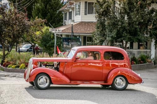 an old red car is driving down the street at Inn on Canyon in Radium Hot Springs
