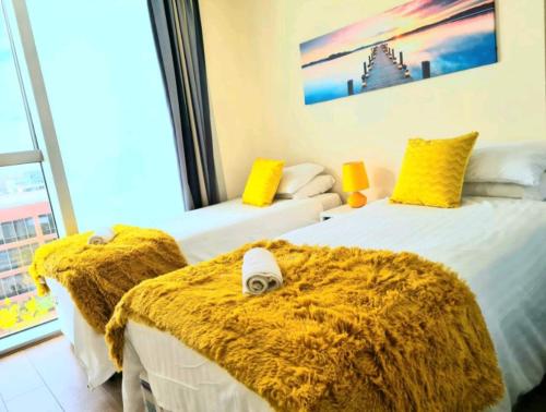 two beds in a room with yellow and white at Blue Diamond in Milton Keynes