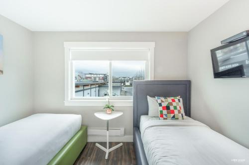 a small bedroom with two beds and a window at Queens Hotel in New Westminster