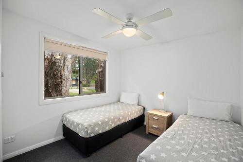 a bedroom with two beds and a ceiling fan at Sapphire Beach Holiday Park in Coffs Harbour