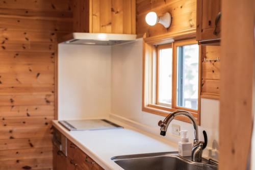 uma cozinha com um lavatório e uma janela em Relaxing Log Cabin IZU HOUSE- Vacation STAY 85769 em Ito