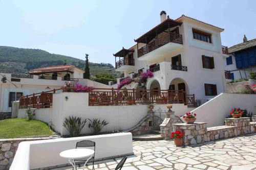 a large white house with a table and chairs at Pleoussa Studio and Apartments in Skopelos Town