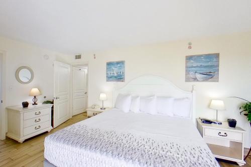 a white bedroom with a white bed and two night stands at Bay Watch 1941 in Myrtle Beach