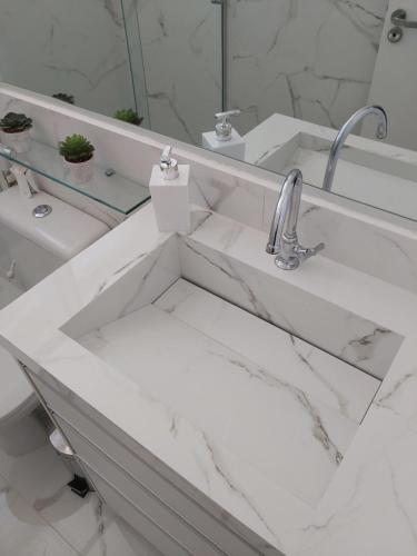 a white bathroom with a sink and a mirror at Apto 2 dorms WIFI Grátis Zona Sul in Ribeirão Preto